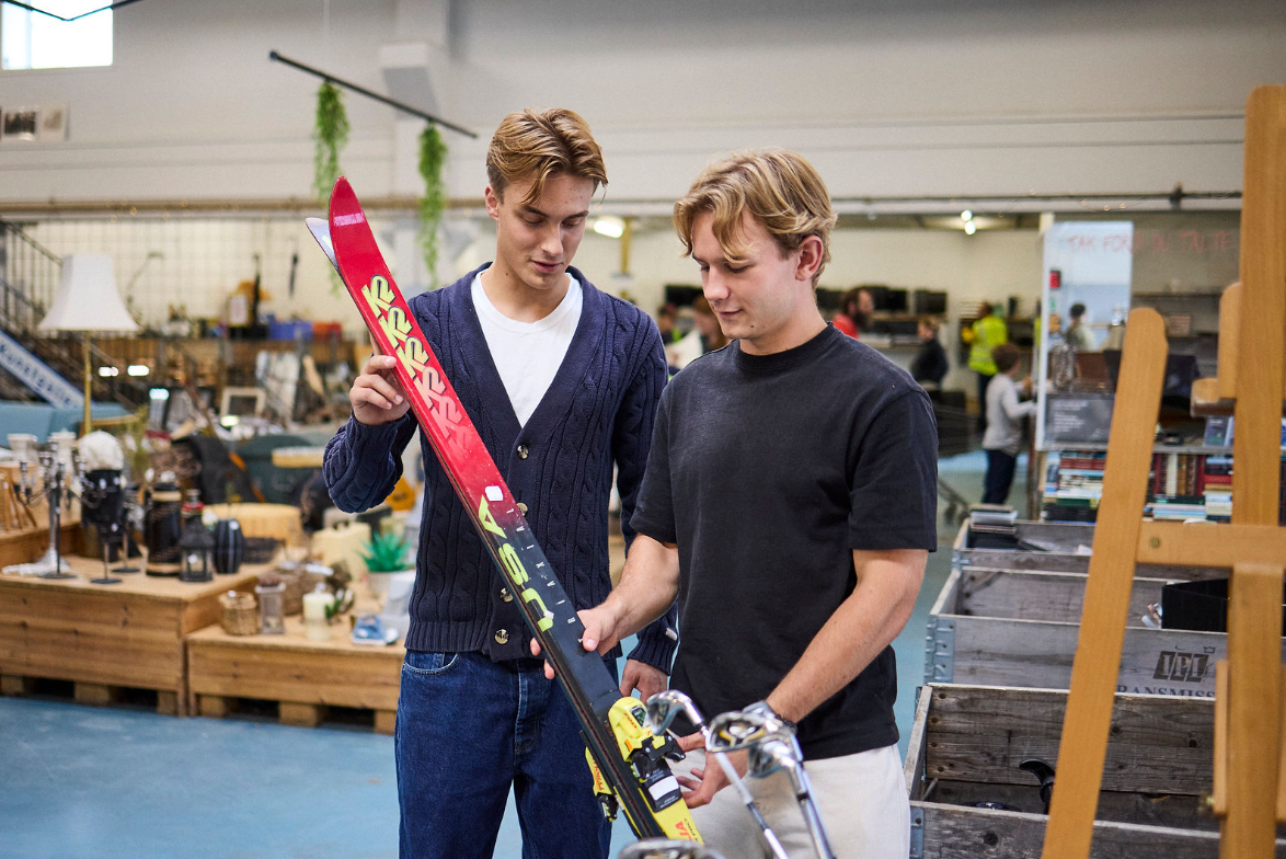 To unge mænd der står med et par ski i hånden